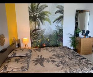 una camera da letto con un letto con un murale di palme sul muro di Studio Cap Caraibes, piscine, accès plage, nouvelle Wifi haut debit a Saint-François
