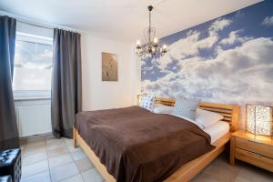um quarto com uma cama com uma pintura de nuvens em Appartement-Badeweg-5-BAD-501 em Scharbeutz