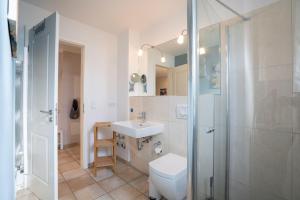 uma casa de banho com um WC, um lavatório e um chuveiro em Appartement-Badeweg-5-BAD-501 em Scharbeutz