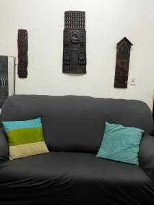 a black couch with pillows in a room with a wall at Cantinho do Thiê in Paquetá