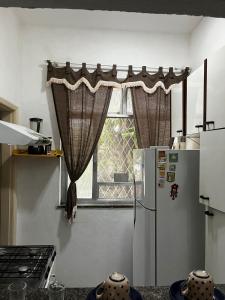 a kitchen with a window with curtains and a refrigerator at Cantinho do Thiê in Paquetá