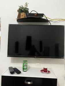 a flat screen tv on a wall with two remote controls at Cantinho do Thiê in Paqueta