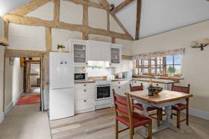 een keuken met witte apparatuur en een houten tafel bij Gardeners Cottage near Ledbury in Ledbury