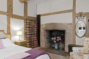 een slaapkamer met een open haard, een bed en een stoel bij Gardeners Cottage near Ledbury in Ledbury