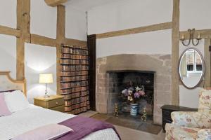 a bedroom with a fireplace with a bed and a chair at Gardeners Cottage near Ledbury in Ledbury