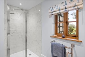 La salle de bains est pourvue d'une douche en verre et d'une fenêtre. dans l'établissement Gardeners Cottage near Ledbury, à Ledbury
