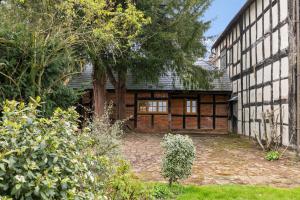 an exterior view of a house with trees and bushes at Gardeners Cottage near Ledbury in Ledbury