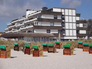 - une rangée de chaises de plage sur le sable devant un bâtiment dans l'établissement TER-101-Terrassenhuegel-Teilseeblick, à Scharbeutz