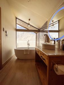 a bathroom with a tub and a sink and a mirror at Khoj Resorts in Shigar