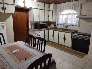 a kitchen with white cabinets and a table with chairs at Casa do Nonno na Montanha in Campos do Jordão