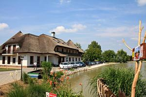 a building with a thatched roof next to a river at Penzión Eko Park Piešťany in Piešťany