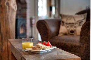 a table with a plate of bread and strawberries and a glass of orange juice at Auberge le Cosy in La Conception