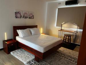 盧薩卡的住宿－Smart Stay Eco Friendly AirBnB，一间卧室配有一张床和一张桌子及凳子