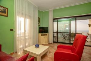 un soggiorno con divano rosso e sedia rossa di Appartamento fronte mare con parcheggio gratuito a Pizzo