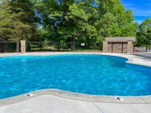 a blue swimming pool with a fence and trees at 3BR Walk-In with Loft - Pool and Hot Tub - FREE ATTRACTION TICKETS INCLUDED - PARA in Branson