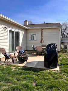 eine Terrasse mit Stühlen, einem Sonnenschirm und einem Grill in der Unterkunft House w Patio & Fenced Yard 10 minutes to Purdue in Lafayette