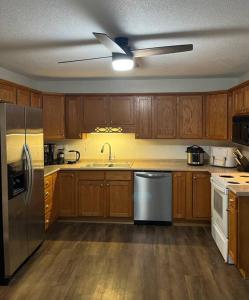 eine Küche mit Holzschränken und einem Kühlschrank aus Edelstahl in der Unterkunft House w Patio & Fenced Yard 10 minutes to Purdue in Lafayette