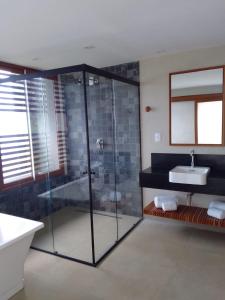y baño con ducha acristalada y lavamanos. en Pousada Ecológica Akanã en Fernando de Noronha