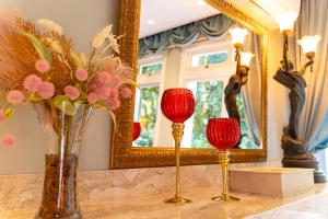 two vases with red candles on a table in front of a mirror at Le Boutique Hotel Gramado - Exclusivo para Casais in Gramado