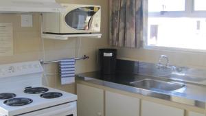 a kitchen with a stove and a sink and a microwave at Cromwell Motel in Cromwell