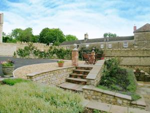 a garden with a stone wall and stairs in front of a house at The Wagon House in Wellow
