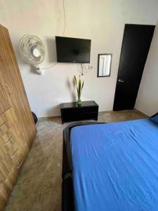 a bedroom with a blue bed and a fan at Acogedor apartamento en conjunto residencial in Soledad