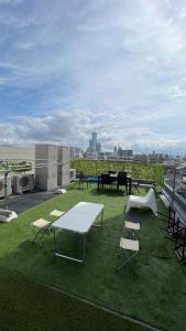 eine Terrasse mit Tischen und Stühlen auf einem Dach in der Unterkunft 難波南34 in Osaka