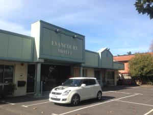 a white car parked in a parking lot in front of a building at Evancourt Motel Malvern East in Melbourne