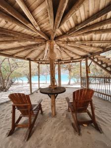 une table et deux chaises sous un parasol en bois dans l'établissement Wachakyta Ecolodge, à Calabazo