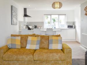 a living room with a couch and a kitchen at Beach Cottage in Benllech