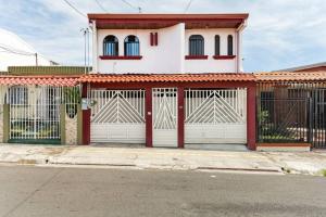 ein weißes Haus mit einem roten und weißen Tor in der Unterkunft Private bedroom 10 minutes from the SJO airport in Alajuela