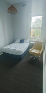 ein Schlafzimmer mit einem Bett, einem Stuhl und einem Fenster in der Unterkunft Leura Hotel in Camperdown