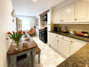 una cocina con armarios blancos y una mesa con flores. en Wisteria Cottage, en Uppingham