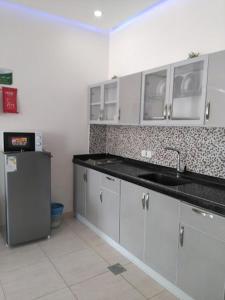 a kitchen with white cabinets and a sink and a refrigerator at منتجع الجزيرة الخضراء in Al Hada