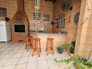 a kitchen with three bar stools and a counter at Pousada 218 Manaus in Manaus