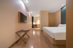 a bedroom with a bed and a tv on a wall at Ibis Styles XM Zhongshan Hotel in Xiamen