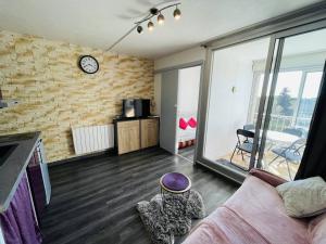 salon z kanapą i zegarem na murze. w obiekcie Studio Cabine au Calme, Proche Port et Plage, Parking Gratuit - FR-1-723-96 w Cap d'Agde