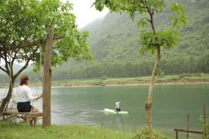 una persona en una tabla de surf de remo en el agua en Phong Nha A Little Leaf Homestay en Phong Nha