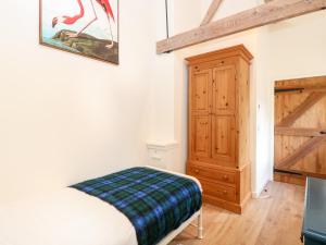 a bedroom with a bed and a wooden cabinet at The Granary in East Dereham
