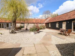 a garden with a table and a tree and a building at The Granary in East Dereham