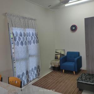 uma sala de estar com uma cadeira azul e uma janela em Sri Bayu Bidara Palma em Masjid Tanah