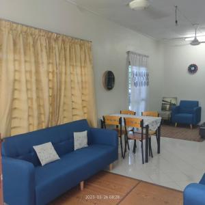 Sri Bayu Bidara Palma في مسجد طنة: غرفة معيشة مع أريكة زرقاء وطاولة