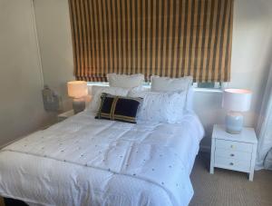 um quarto com uma cama branca, 2 candeeiros e uma janela em CBD Apartment, River View em Hamilton