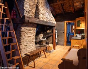 a kitchen with a stone fireplace with a wooden bench at Haus Zer Trächu in Saas-Almagell