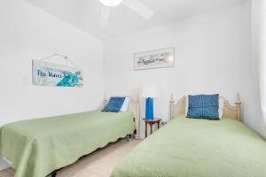 2 camas en una habitación con paredes blancas en Moon Tide Cottage, en Pensacola Beach