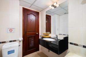a bathroom with a sink and a toilet and a wooden door at LUCASTA SAIGON Hotel in Ho Chi Minh City