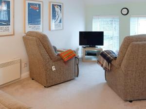a living room with two chairs and a television at The Loft in Warkworth