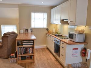 a kitchen with white cabinets and a counter with a microwave at The Loft in Warkworth