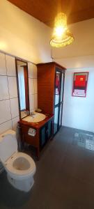 een badkamer met een toilet, een wastafel en een kroonluchter bij Surigao Dream Beach Resort in Tigbao