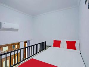 ギャニャールにあるTiny House Gianyarのベッドルーム(白いベッド、赤い枕付)